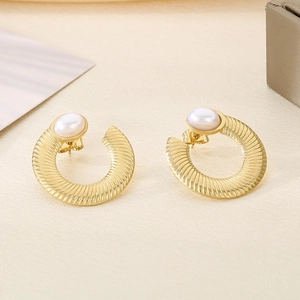 Detailed view of gold C-shaped twisted earrings with pearls and brushed metal texture