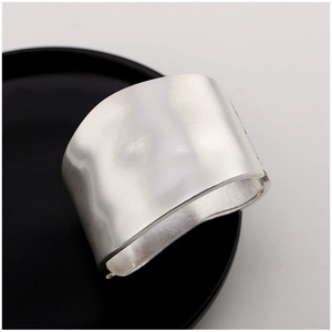 Macro view of wide silver brushed metal cuff bracelet with elegant hinge closure
