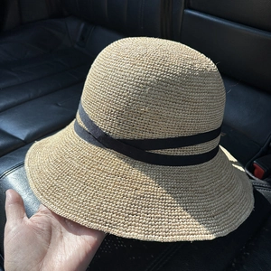 Detail eines handgewebten Raffia-Strohhuts in Beige mit elegantem schwarzem Dekoband