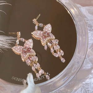 Détail de boucles d'oreilles papillon en zircon rose avec pampilles en cristal sur miroir doré