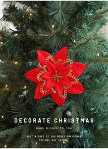 Vibrant red Christmas flower with gold glitter on a green pine tree branch