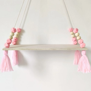 Detail of Nordic wooden hanging shelf with pink octagonal beads and decorative tassels