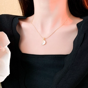 Gros plan d'un collier en acier titane doré avec un pendentif croissant de lune en nacre