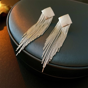 Macro view of silver diamond-shaped metal tassels earrings on a black display pad