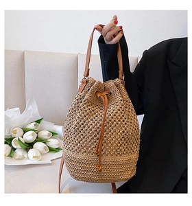 Close-up of woven straw bucket bag with leather handle and drawstring closure
