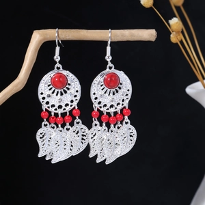 Detail of bohemian drop earrings with red resin stones and silver leaf pendants