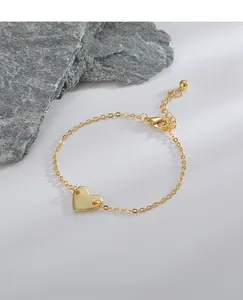 Détail macro du bracelet cœur doré avec lettre D gravée et fermoir mousqueton