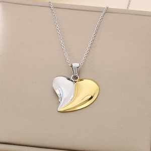 Detailed macro of a two-tone gold and silver heart pendant on a thin O-chain necklace