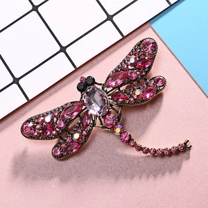 Detailed close-up of a dragonfly brooch featuring pink rhinestones and crystals