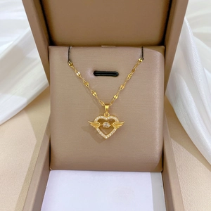 Macro view of golden heart pendant with angel wings and zircon inlay in a gift box