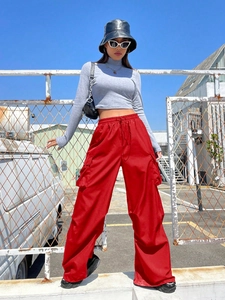 Detail of red high-waist cargo pants with drawstring and large utility pockets