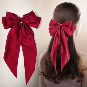 Detailed shot of large red satin bow hair clip with long ribbons and smooth texture