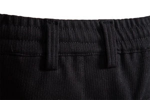 Macro detail of black trousers waist featuring elastic band and belt loops on woven fabric