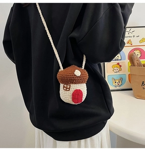 Detailed view of a handmade mushroom-shaped knit crossbody bag on a person's back