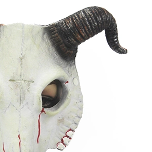 Detail view of white goat skull mask featuring spiral black horns and red blood splatter