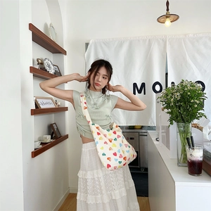Detail of colorful heart pattern canvas tote bag paired with white lace skirt