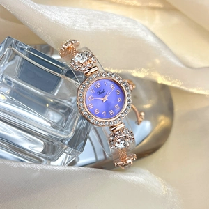 Detail of rose gold bracelet watch with purple dial and rhinestones on silk background