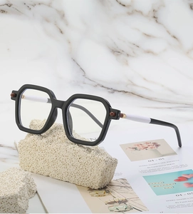 Detail of square black frame sunglasses with bicolor temples on stone and fashion magazine