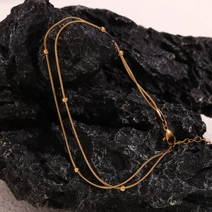 Close-up of double-layer 18K gold-plated bead snake chain bracelet on black rock