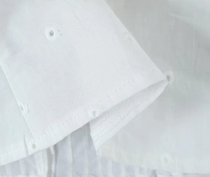 Dettaglio del delicato ricamo Broderie Anglaise su tessuto di cotone bianco da vicino
