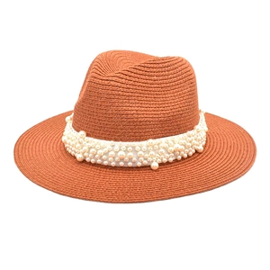 Detail of caramel straw fedora hat featuring woven texture and ornate white pearl embellishment