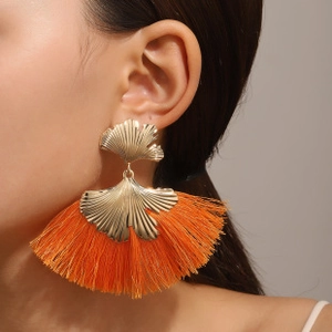 Close-up of golden ginkgo leaf earrings with vibrant orange fan-shaped thread tassels