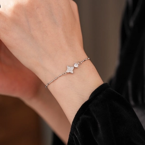 Bracelet étoile argenté élégant avec breloques en zircon porté sur un poignet en velours