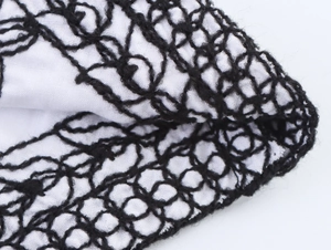 Macro shot of black mesh embroidery on white ethnic vest fabric with textured details