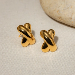 Macro shot of 18k gold plated stainless steel X-shape cross earrings on fabric