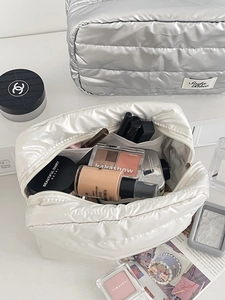 Detailed view of quilted cosmetic bags in silver and beige with spacious inner storage