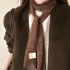 Detail of a brown paisley print fabric scarf necklace with elegant drapery and vintage texture