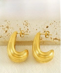 Detailed view of C-shaped gold geometric earrings with elegant wave textures on stone