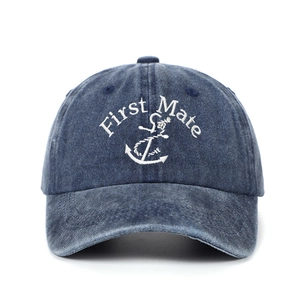 Detail of white First Mate embroidery and anchor on a washed navy blue cotton baseball cap