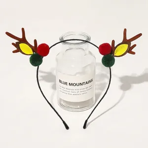 Detail showing plush Christmas reindeer antlers with festive red and green fuzzy pom-poms