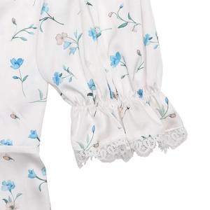 Detail of floral satin sleeve with ruffled cuff and white lace trim on the dress