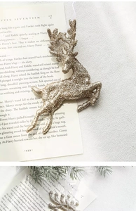 Close-up of golden glitter reindeer ornament with bow on vintage book background