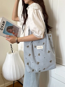 Light blue corduroy tote bag with bear embroidery shown on a female model shoulder
