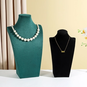 Detail of pearl and gold necklaces on dark green and black velvet jewelry display busts