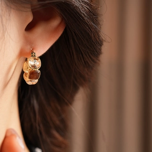 Close-up of vintage gold U-shaped earrings featuring multi-color square cubic zirconia