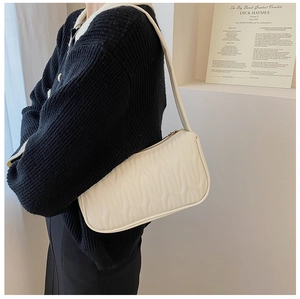Detail of beige faux leather shoulder bag with wavy texture and matching strap