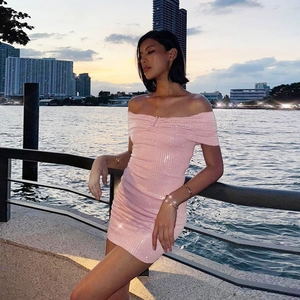 Detail of pink sequin off-shoulder mini dress worn by model at sunset waterfront