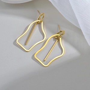 Minimalist irregular hollow geometric gold earrings on a clean white fabric background