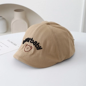 Gros plan sur le béret beige pour enfant avec broderie ours sur un fond minimaliste