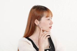 Detailed view of a woman wearing a round geometric stud earring with radiant textures