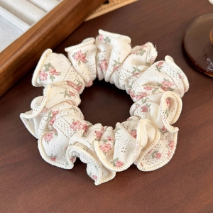 Detailed close-up of cream floral scrunchie with pink rose print and eyelet lace texture