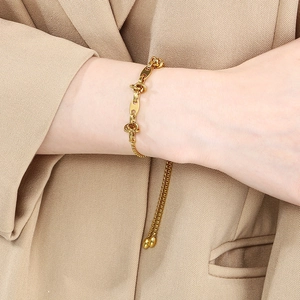 Detail of gold spliced chain bracelet with double tassels on a model's wrist
