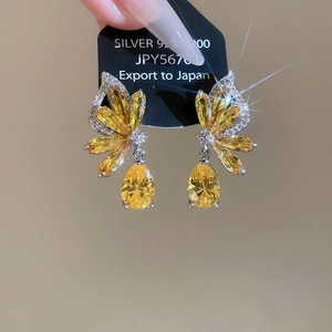 Detailed close-up of 925 silver butterfly earrings with yellow stones and drop pendant
