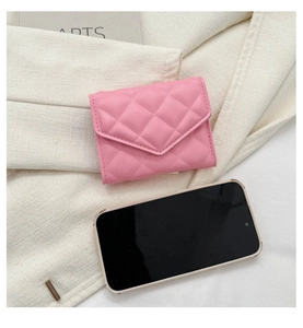 Detail of pink quilted small wallet with smartphone for size comparison on fabric