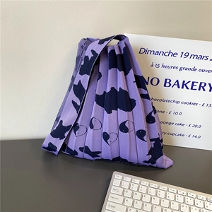 Detail of purple pleated knitted tote bag featuring abstract patterns and soft texture