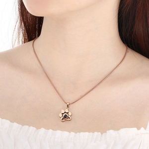Gros plan du pendentif patte de chien or rose avec pierre noire sur chaîne serpent